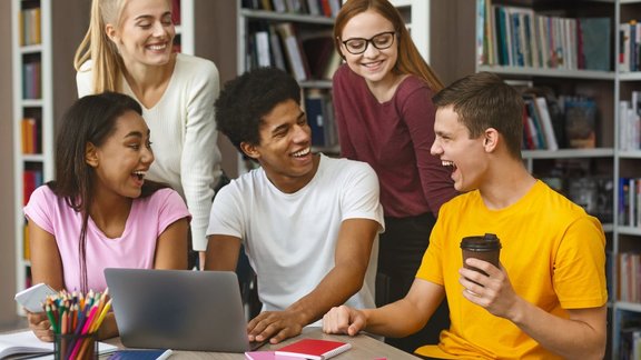 Multinationale Studentengruppe, die an einem Projekt in der Bibliothek arbeitet. Es wird angeregt diskutiert.