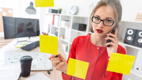 Beautiful young girl in glasses and a red shirt is working in the office. photo with depth of field.