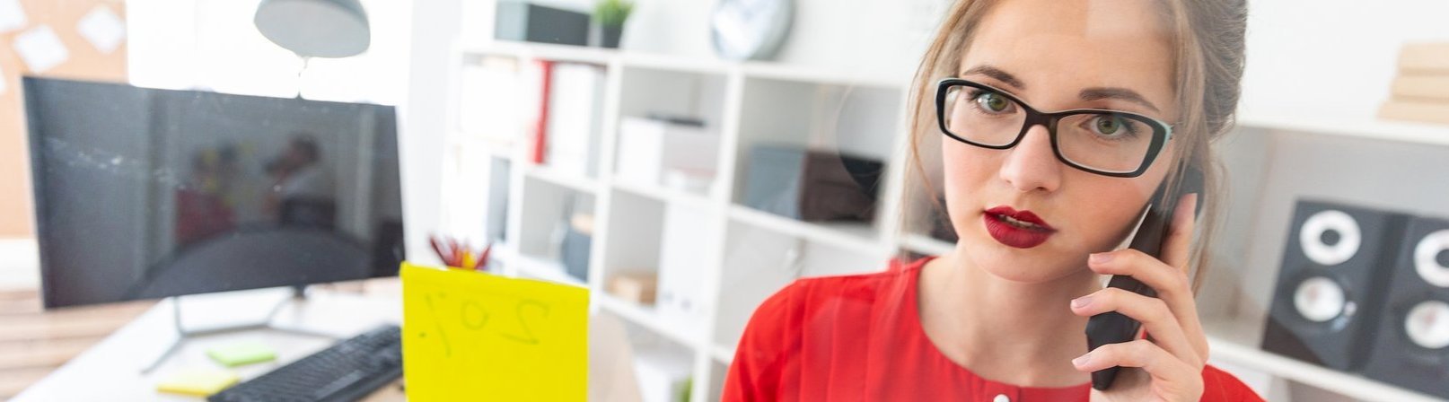 Beautiful young girl in glasses and a red shirt is working in the office. photo with depth of field.